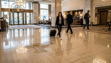 Person examining a wet floor accident scene with caution sign in a commercial property